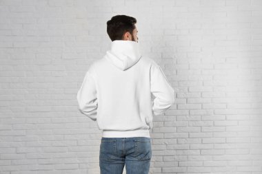 Tuğla duvarda süveter giyen genç bir adam. Tasarım için alay