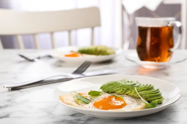 Leckeres Frühstück mit Spiegelei und Avocado auf weißem Marmortisch — Stockfoto