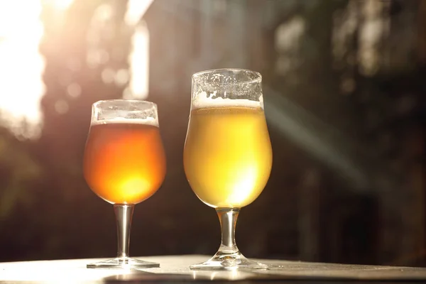 Glazen koud smakelijk bier op houten tafel buiten — Stockfoto
