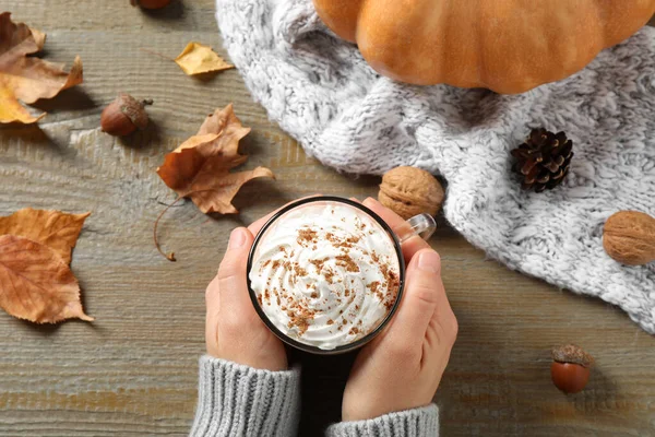 Femme avec tasse de latte aux épices à la citrouille à table en bois, vue sur le dessus — Photo