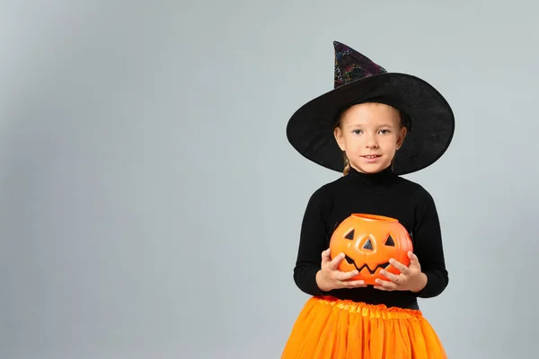 Aranyos kislány tök cukorka vödör visel Halloween jelmez szürke háttér, hely a szöveges — Stock Fotó