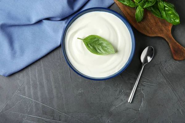 Flat lay composition of sour cream with basil on grey table — Stock Photo, Image