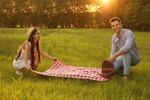 Unga par med picknick filt och korg i parken — Stockfoto