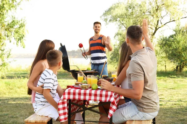 Tineri fericiți și băiețel cu picnic la masă în parc — Fotografie, imagine de stoc