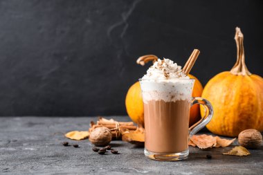 Krem şantili balkabağı aromalı latte ve gri masadaki cam bardakta tarçın çubuğu. Metin için boşluk