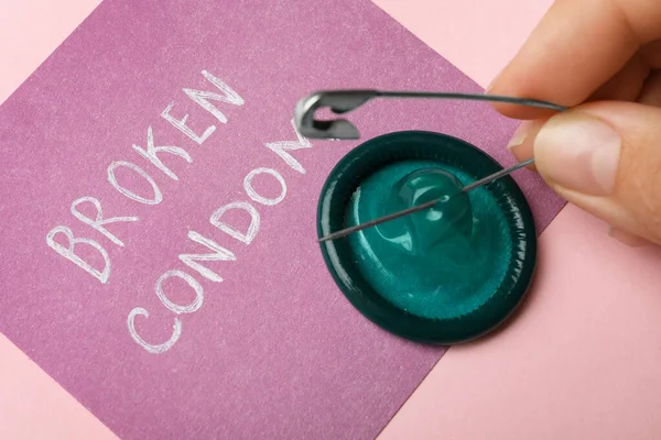 Woman piercing condom with pin on pink background, closeup. Safe sex — Stock Photo, Image