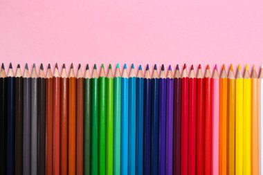 Pembe arka planda renkli kalemler, düz yatış. Metin için boşluk