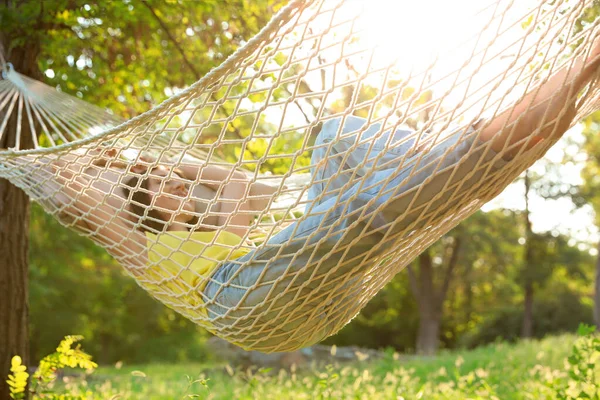 Jovem descansando na rede confortável no jardim verde — Fotografia de Stock