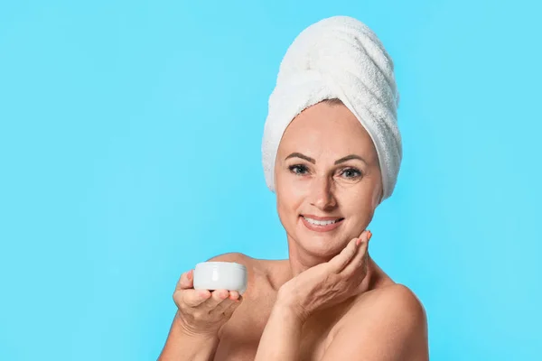 Ritratto di bella donna matura con pelle perfetta che tiene il vaso di crema su sfondo azzurro — Foto Stock