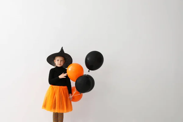 Aranyos kislány, lufikkal halloween jelmezt visel, világos háttérrel. A szöveg helye — Stock Fotó
