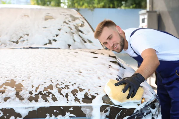 Mladý pracovník čištění automobil s houbou na mytí aut — Stock fotografie