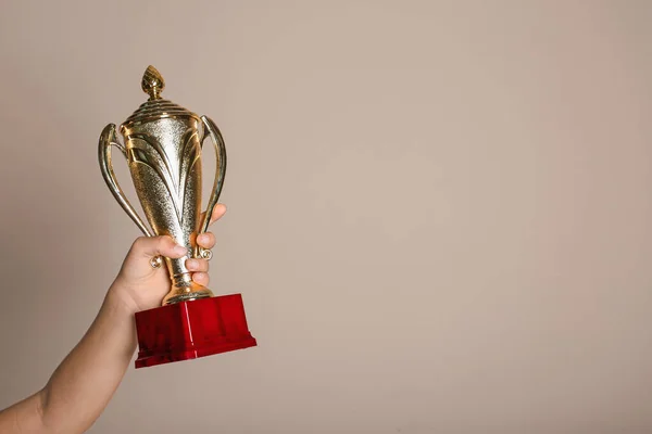 Niño sosteniendo copa ganadora dorada sobre fondo beige, primer plano. Espacio para texto — Foto de Stock