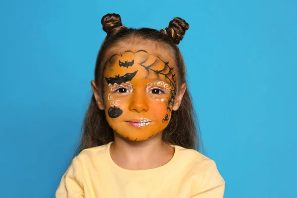 Schattig klein meisje met gezicht schilderen op blauwe achtergrond — Stockfoto