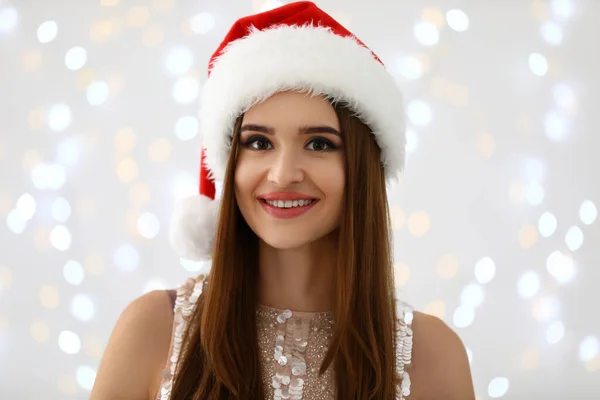 Noel Baba şapkalı mutlu genç kadın bulanık Noel ışıklarına karşı — Stok fotoğraf