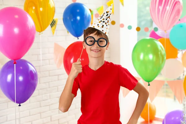 Niño feliz cerca de globos brillantes en la fiesta de cumpleaños en el interior —  Fotos de Stock