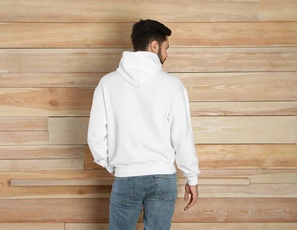 Молодий чоловік у светрі біля дерев'яної стіни. Макет для дизайну — стокове фото