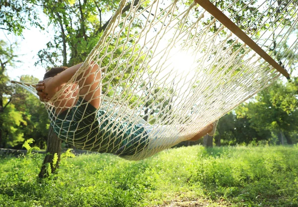 Jeune homme reposant dans un hamac confortable au jardin vert — Photo