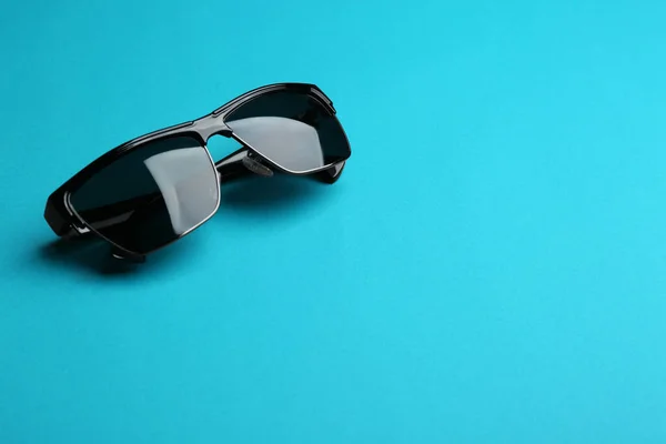 Stijlvolle zonnebril op blauwe achtergrond, ruimte voor tekst. Modieus accessoire — Stockfoto