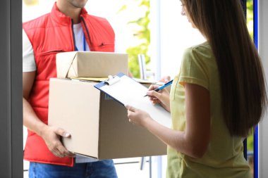 Kapıda paket teslim eden bir kadın var. Kapıya yakın. Kurye servisi