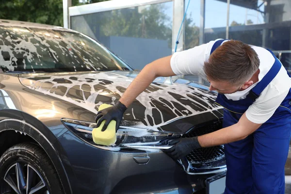 Jovem trabalhador de limpeza automóvel com esponja na lavagem de carro — Fotografia de Stock