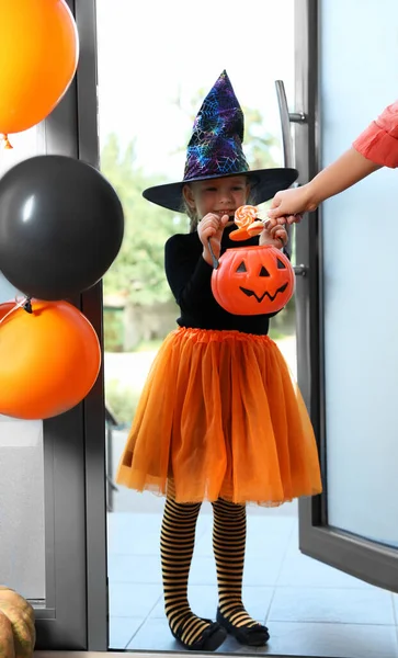 Linda niña vestida como bruja truco o trato en la puerta. Tradición Halloween —  Fotos de Stock