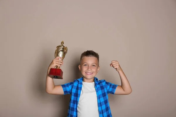 Ευτυχισμένο αγόρι με χρυσό κύπελλο νίκης σε μπεζ φόντο — Φωτογραφία Αρχείου