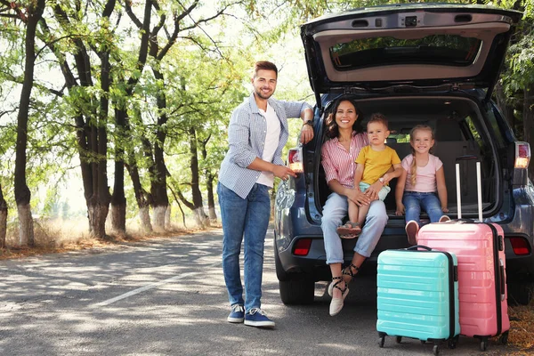 Família feliz perto do porta-malas do carro no dia ensolarado. Viagem de carro — Fotografia de Stock