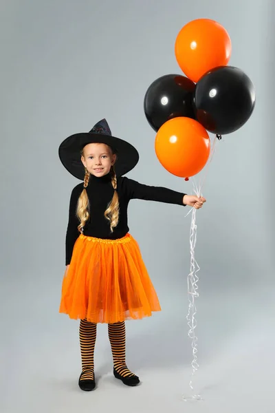 Linda niña con globos con disfraz de Halloween sobre fondo gris —  Fotos de Stock