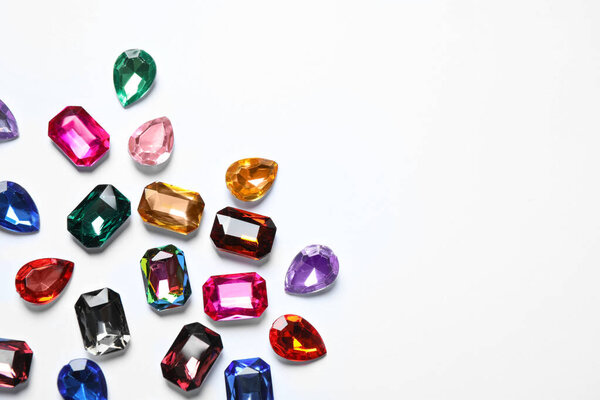 Different beautiful gemstones on white background, top view