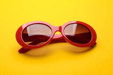 Sarı arka planda şık güneş gözlükleri. Modaya uygun aksesuarlar.