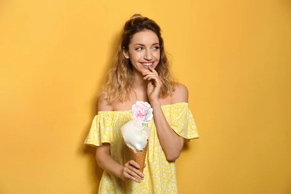 Retrato de mujer joven sosteniendo postre de algodón de azúcar sobre fondo amarillo —  Fotos de Stock