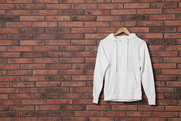 Hanger met nieuwe trui aan bakstenen muur, model voor ontwerp — Stockfoto
