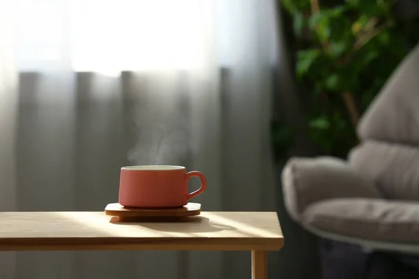 Cup med varm dryck på träbord mot suddig bakgrund. Plats för text — Stockfoto