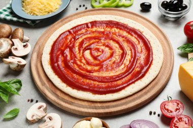 Gri masa üzerinde pizza hamuru ve malzemeleri olan kompozisyon