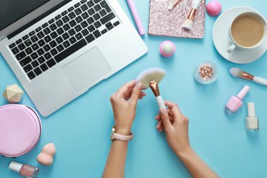 Açık mavi arka planda fırçası ve aksesuarları olan genç bir güzellik blogcusu, üst görünüm