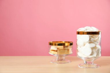 Pamuklu kavanozlar ve ahşap masada pembe arka planda sabun. Metin için boşluk