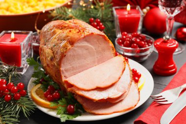 Lezzetli bir Noel jambonu, karanlık masada garnitürle servis edilir.