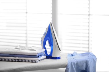 İçinde modern ütü ve giysi yığını olan tahta, yazı için yer. Çamaşır günü