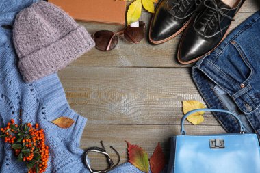 Düz kompozisyon, kalın giysiler ve sonbahar yaprakları ahşap arka planda, metin için boşluk