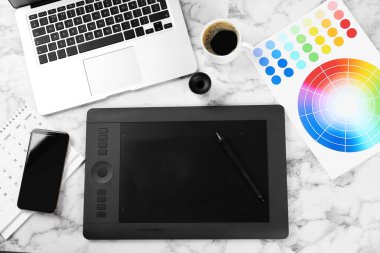 Beyaz mermer masa üzerinde grafik tablet, telefon ve renk paleti ile düz kompozisyon, metin için boşluk. Tasarımcının işyeri