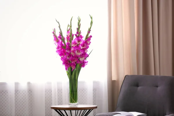 Ваза з красивими рожевими квітами гладіолусів на дерев'яному столі в кімнаті, простір для тексту — стокове фото