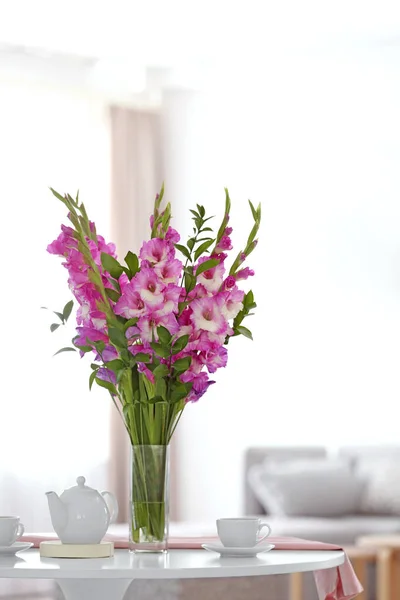 Jarrón con hermosas flores de gladiolo rosa en la mesa de madera en la sala de estar —  Fotos de Stock