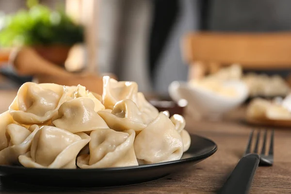 Läckra dumplings med smör på träbord mot suddig bakgrund — Stockfoto