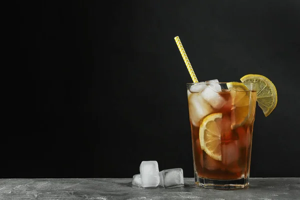 Glas heerlijke ijsthee op grijze tafel tegen zwarte achtergrond. Ruimte voor tekst — Stockfoto