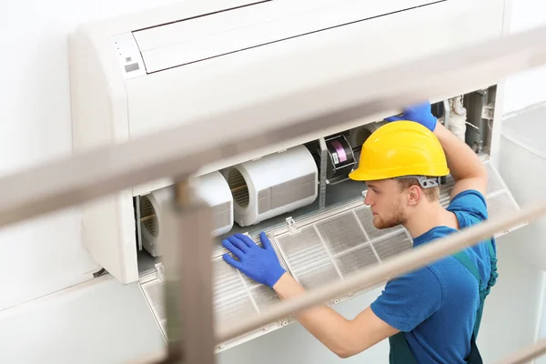 Técnico profissional mantendo ar condicionado moderno dentro de casa — Fotografia de Stock