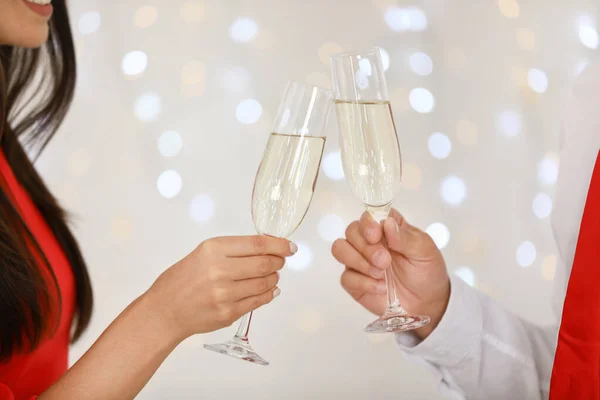 Lovely young couple with glasses of champagne against blurred festive lights, closeup. Christmas celebration — Stock Photo, Image