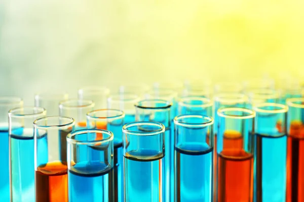Vista de perto de muitos tubos de ensaio com amostras líquidas diferentes, efeito de tom de cor — Fotografia de Stock