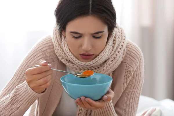 Syg ung kvinde spiser suppe til at helbrede influenza derhjemme - Stock-foto