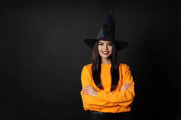 Hermosa mujer con traje de bruja para la fiesta de Halloween sobre fondo negro, espacio para el texto —  Fotos de Stock