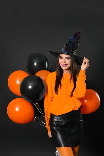 Hermosa mujer con traje de bruja con globos para la fiesta de Halloween sobre fondo negro —  Fotos de Stock